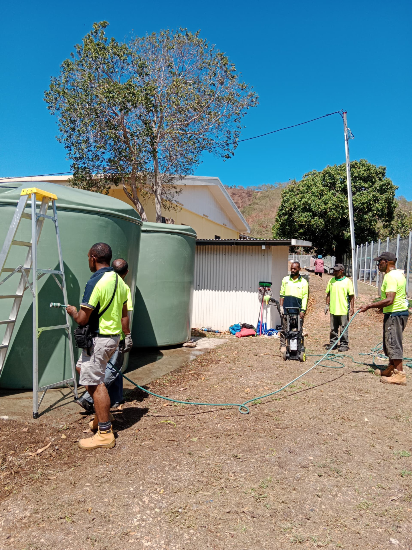 Crew and cleaning equipment beside upright water tanks